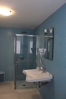 Une salle de bain avec une douche à parois de verre, un lavabo avec un miroir et des murs recouverts de carreaux bleus.