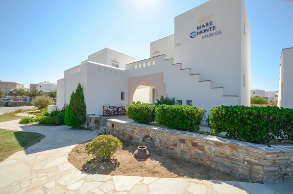 A modern building with a white facade, a stone pathway, and greenery. - Mare Monte (Naxos)
