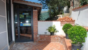 A reception area with a glass door, a brick wall, and potted plants.