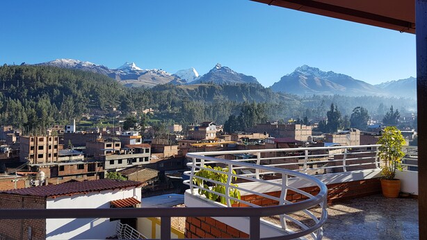 A balcony with a view of a mountainous landscape and a town below.