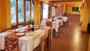 A restaurant with long tables, white tablecloths, and red table runners.
