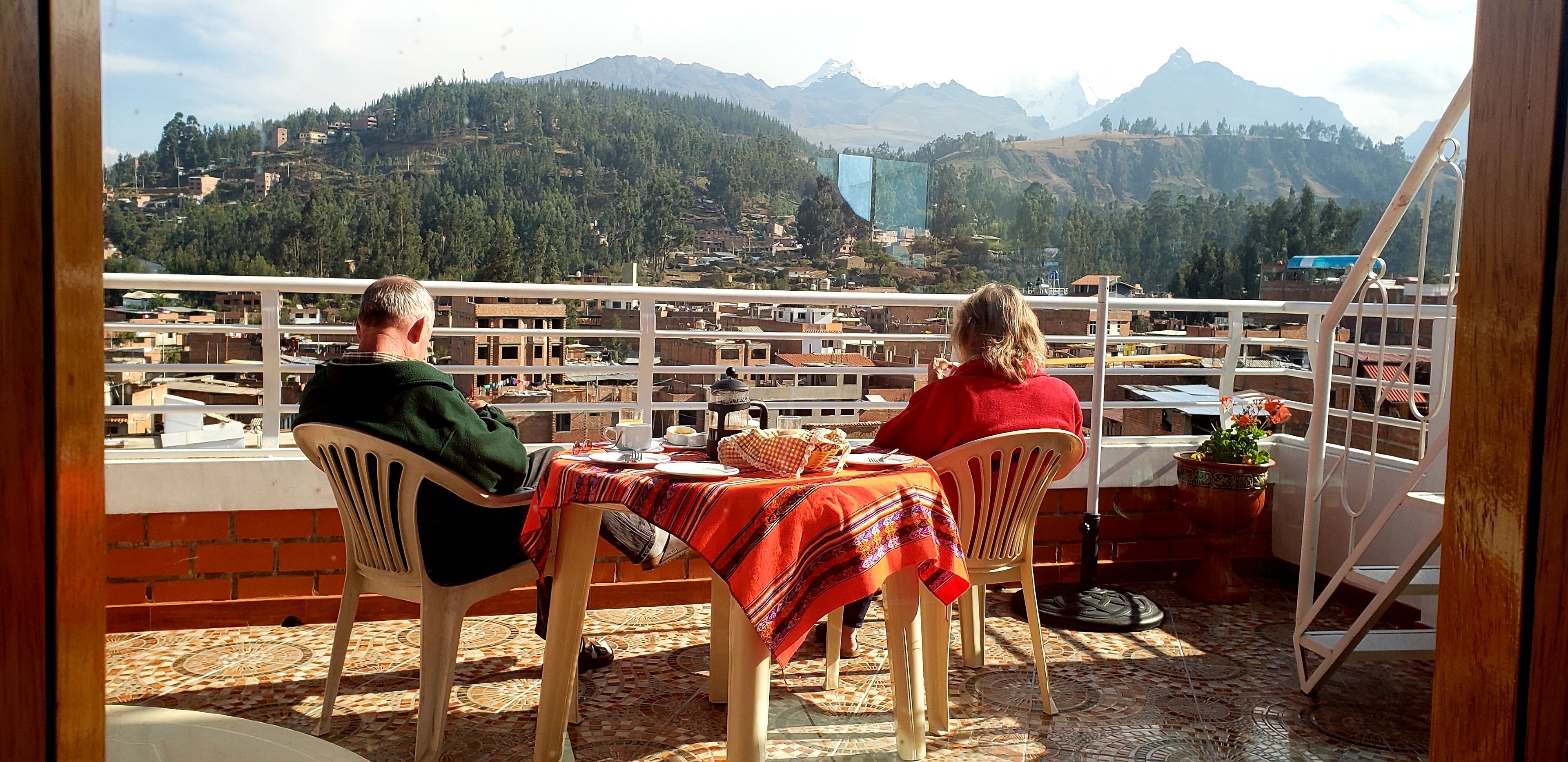 Two people seated at a table with a view of a mountainous landscape.