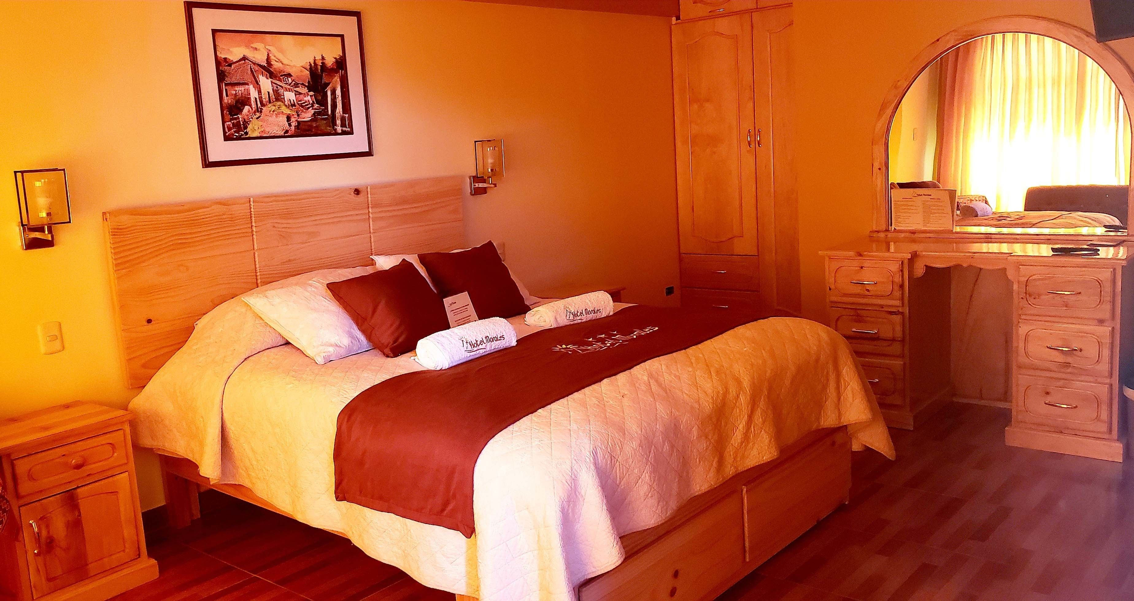 A neatly arranged bedroom with a bed, bedside tables, a dresser, and a mirror.
