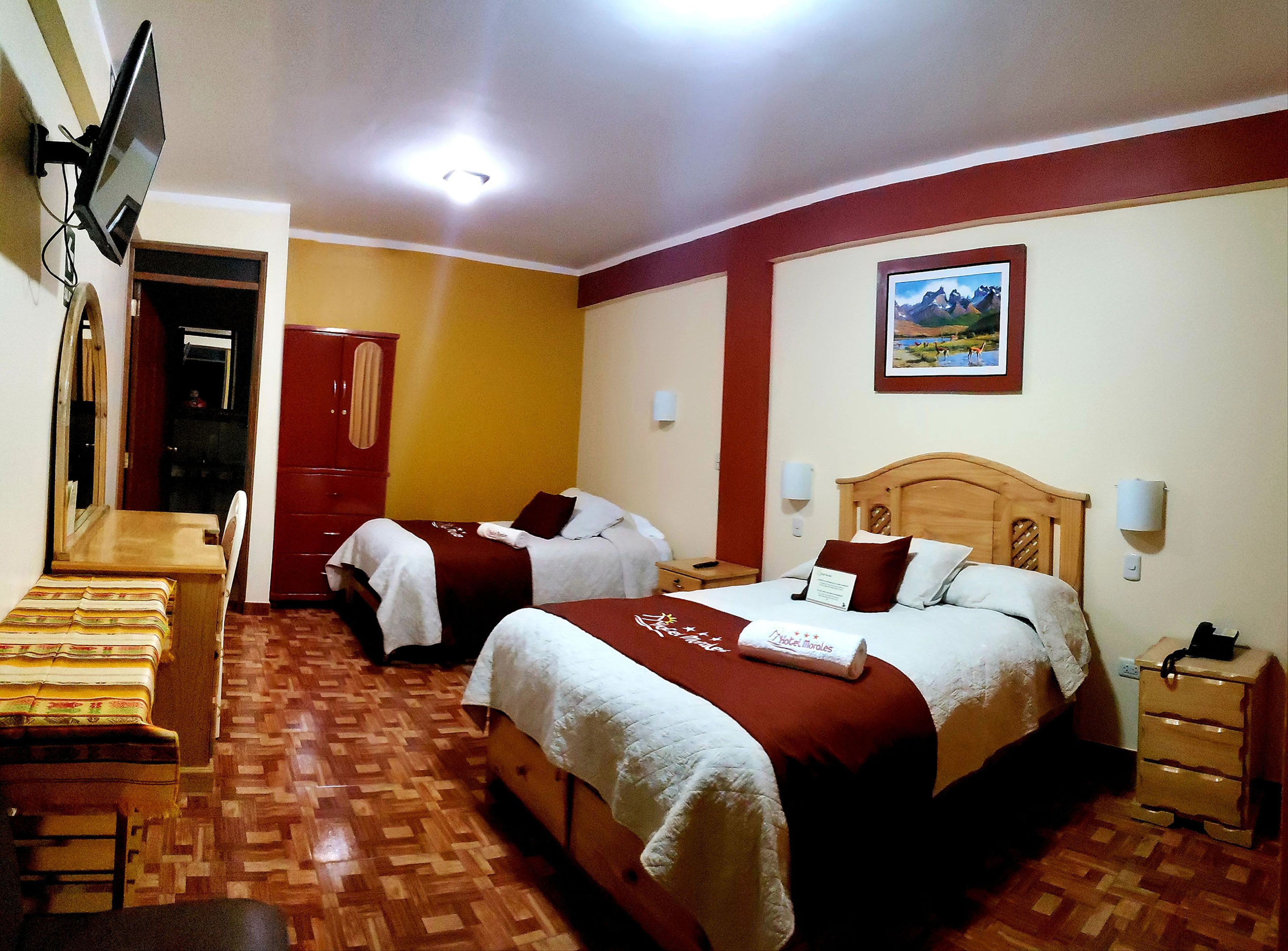 Habitación de hotel con dos camas, un escritorio, un espejo y un televisor.