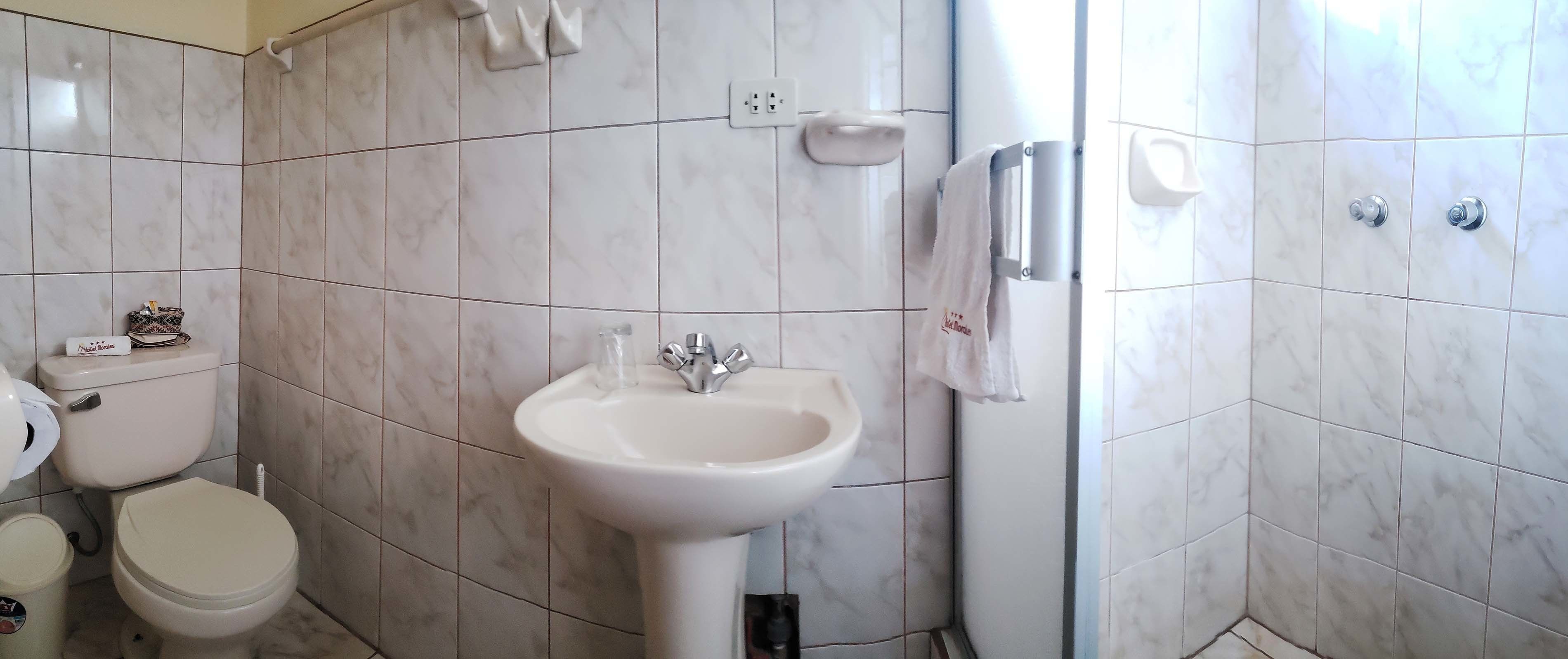 Une salle de bain comprenant des toilettes, un lavabo et un espace douche.