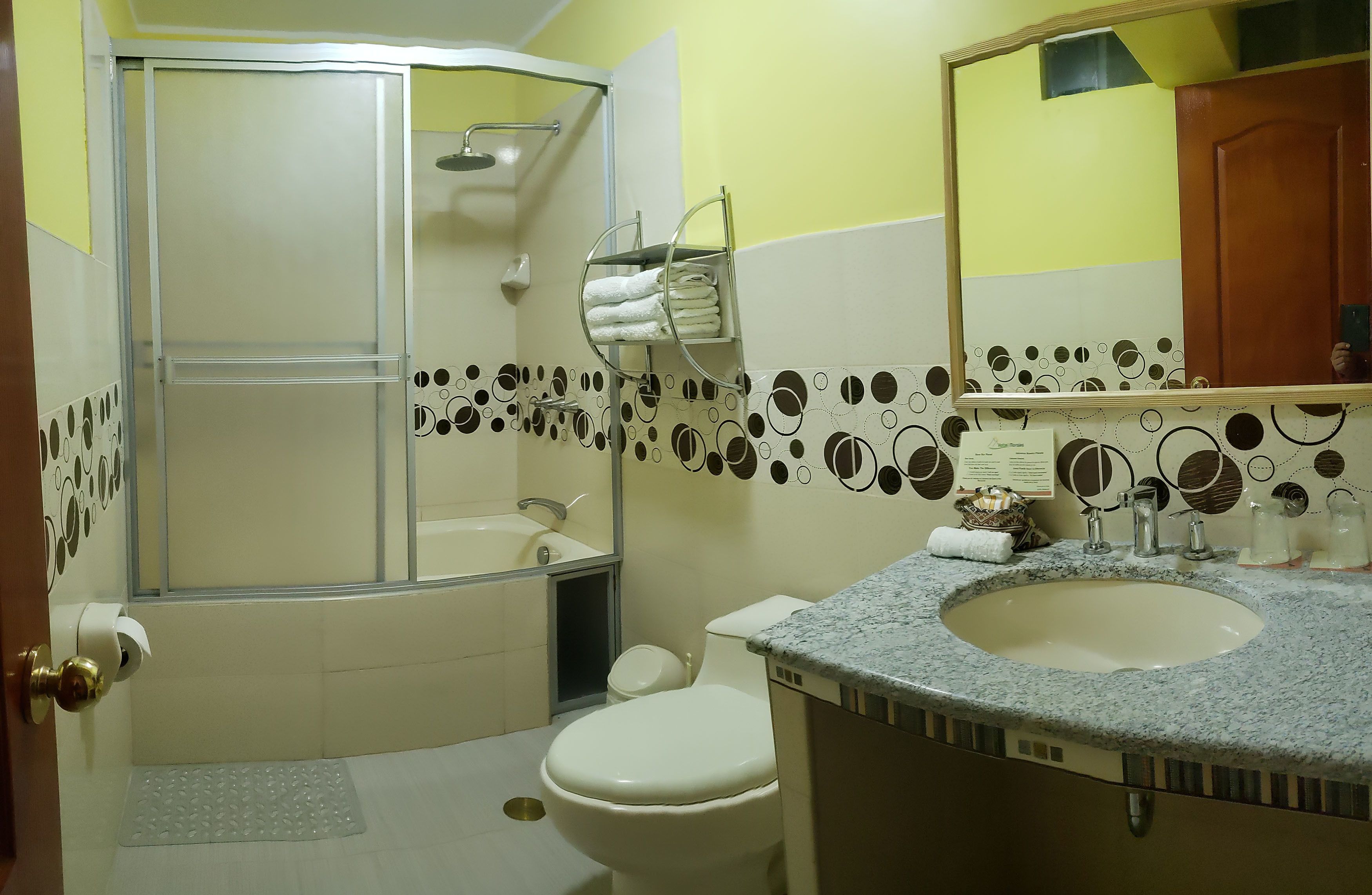 A bathroom with a shower, toilet, sink, and a towel rack.