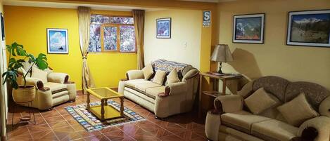 A living room with two sofas, a coffee table, a lamp, and a window with curtains.