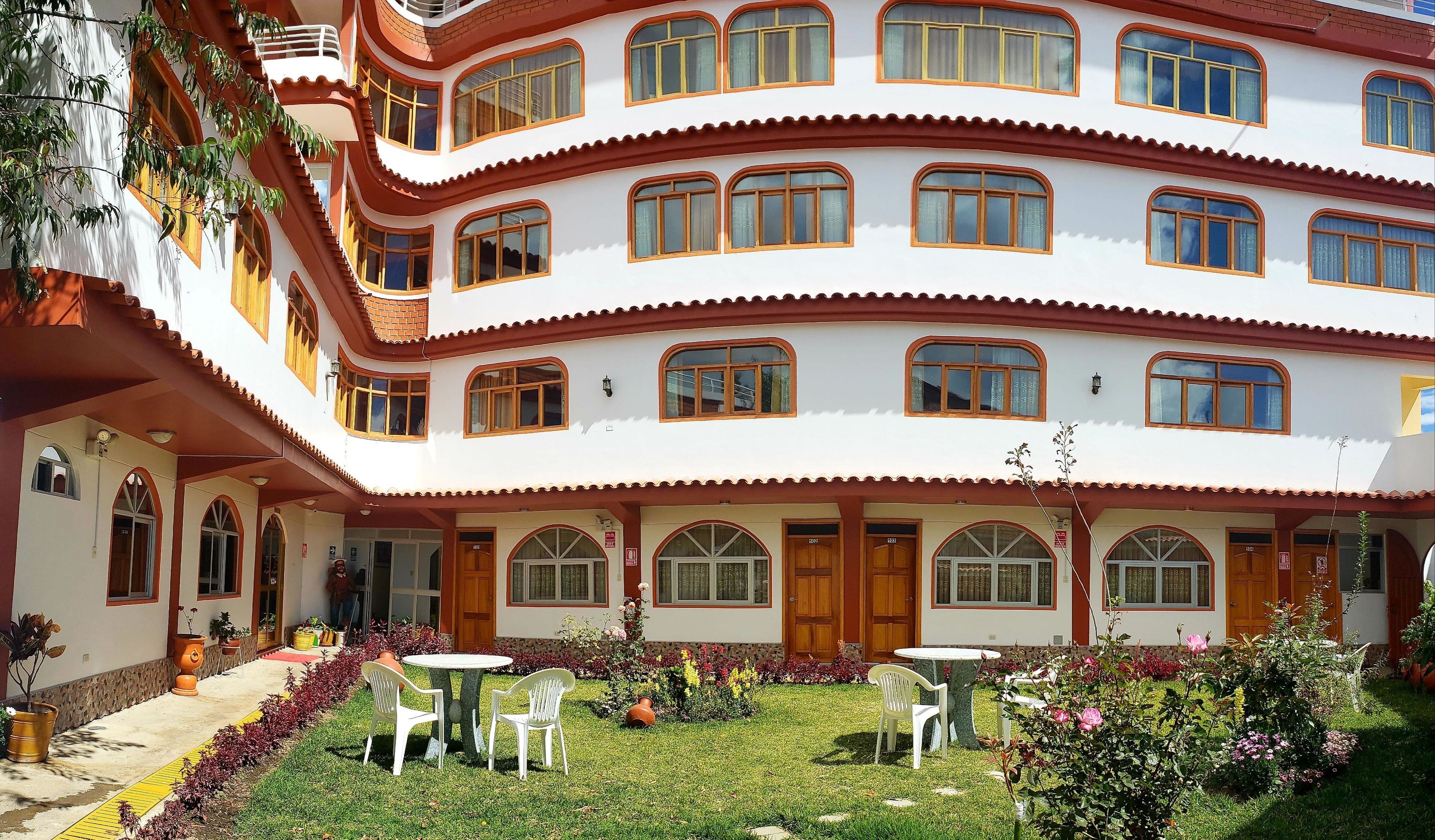 A multi-story building with a white facade and red accents, featuring multiple balconies and large windows.