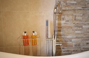 Une salle de bain avec une baignoire, une douche et un mur en pierre.
