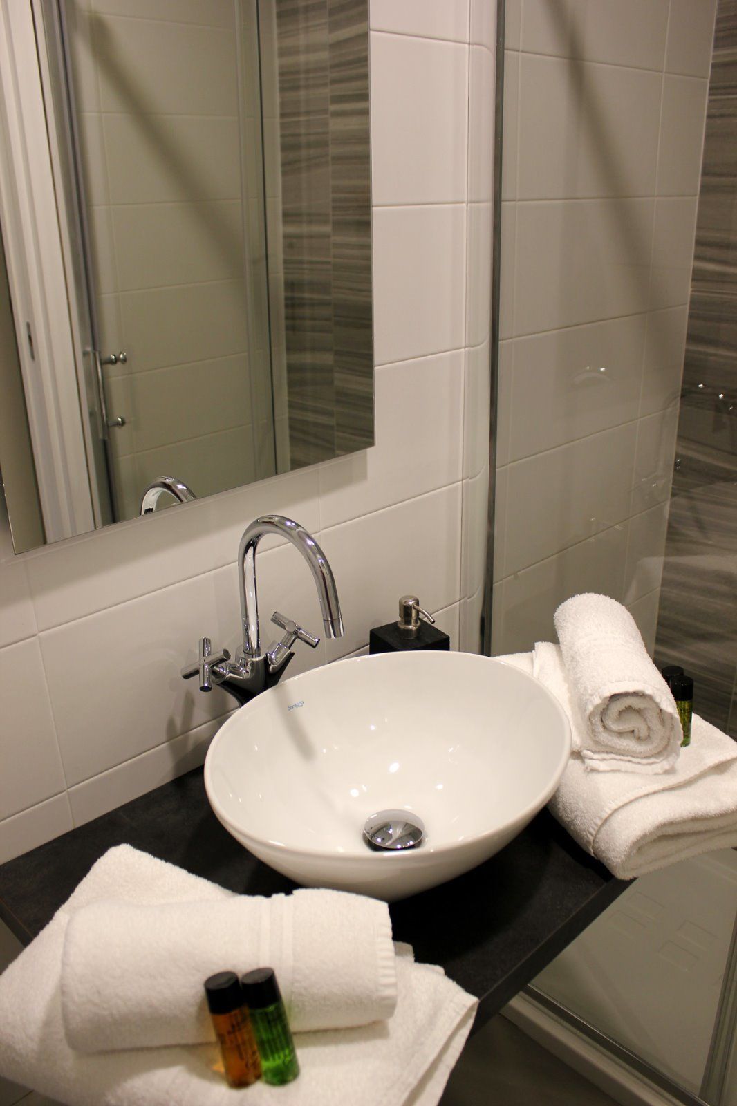 A bathroom with a white sink, a mirror, and a shower.
