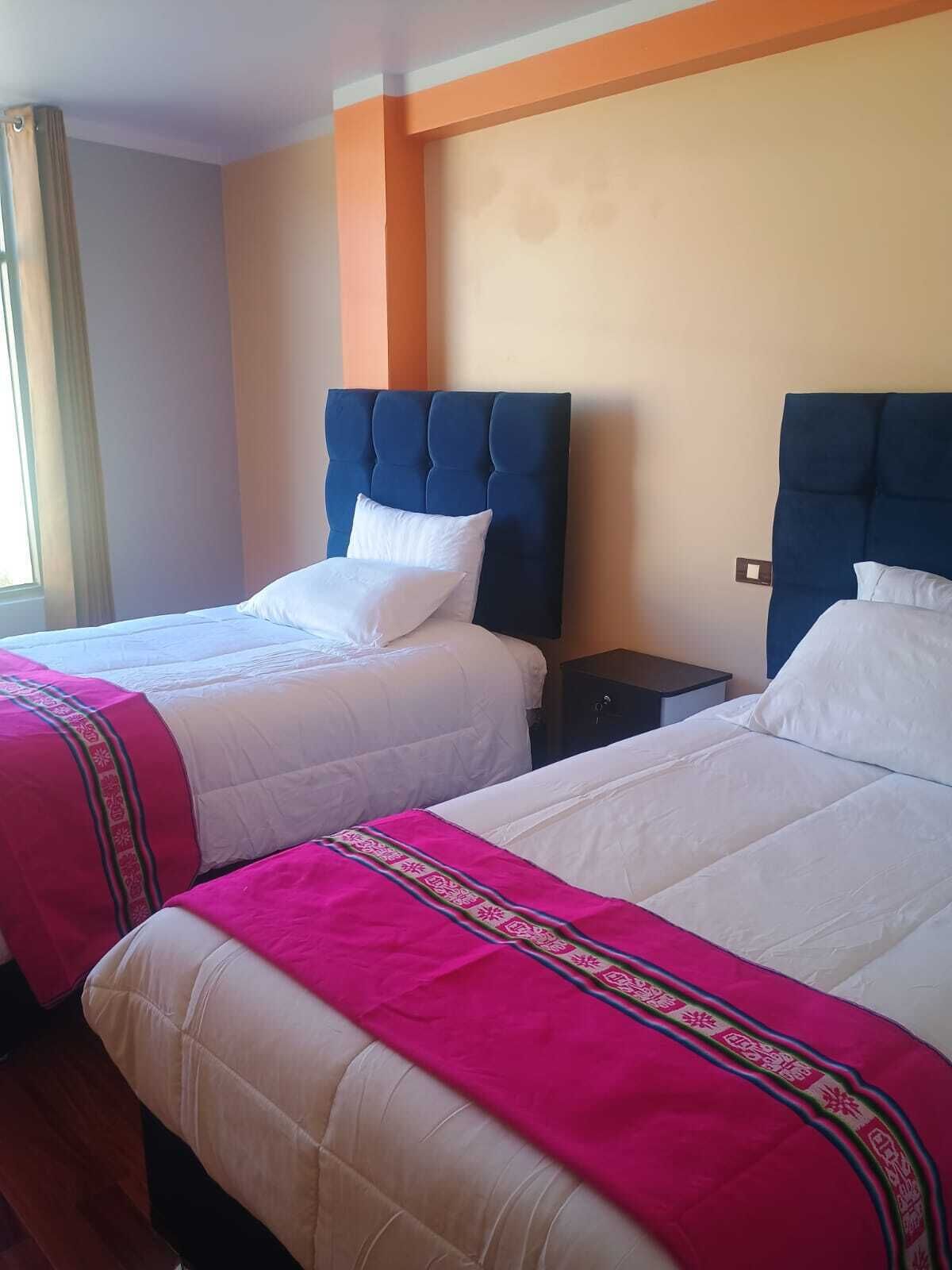 A hotel room with two beds, each with a headboard, white bedding, and a pink decorative border.