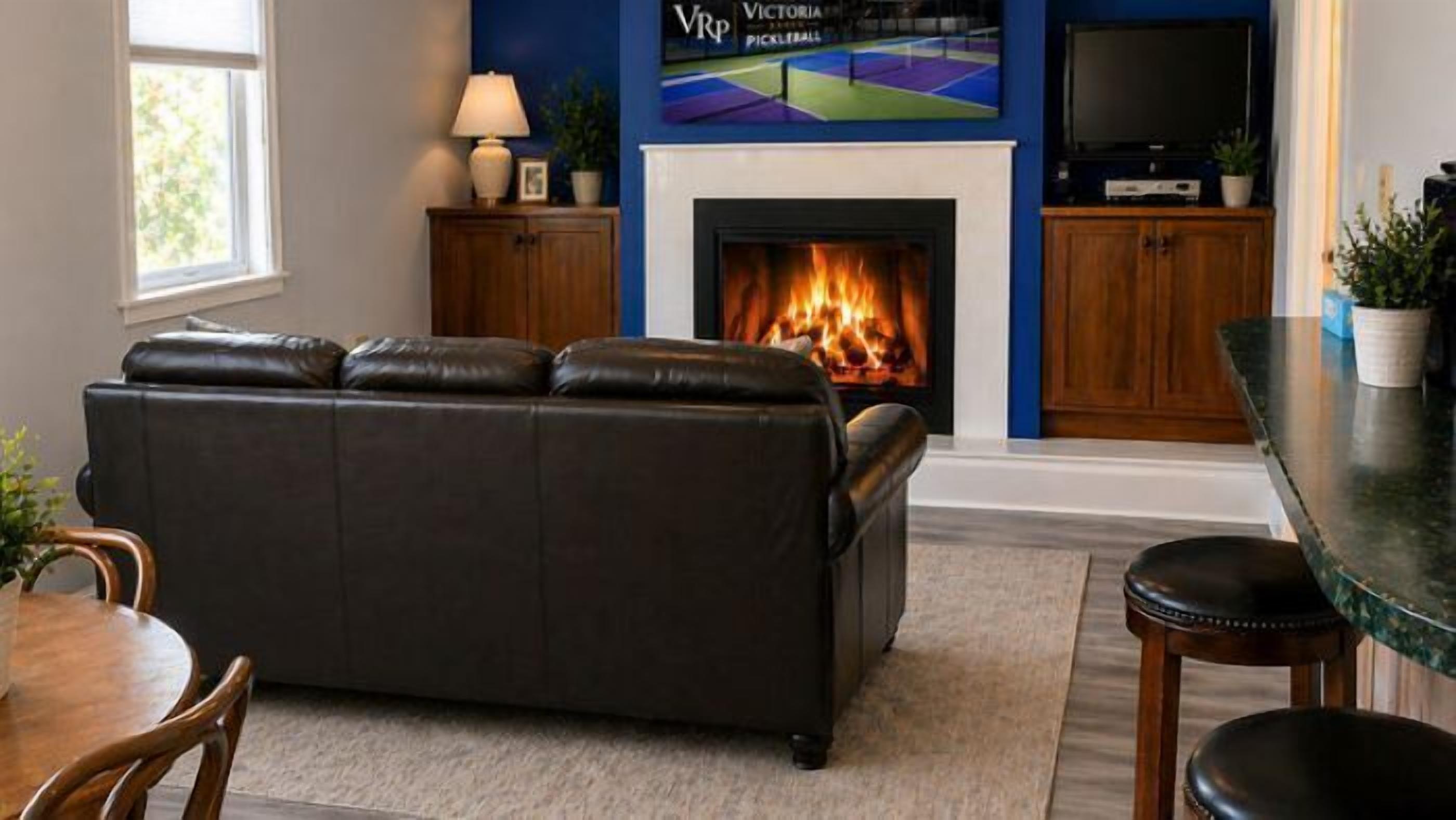 A living room with a fireplace, a sofa, a TV, and a dining area.