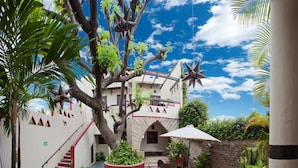 Un patio con un árbol, mesas al aire libre y un edificio con un letrero.