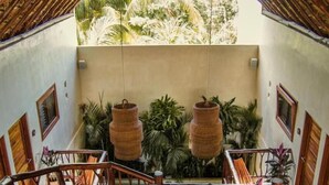 Una escalera con barandilla de madera que lleva a un balcón con vistas a plantas tropicales.