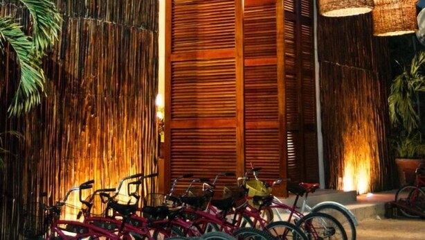 Un edificio con fachada de bambú, una puerta de madera y bicicletas estacionadas en frente.