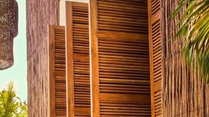 Una estructura de madera con listones verticales, una bicicleta y una planta en maceta.