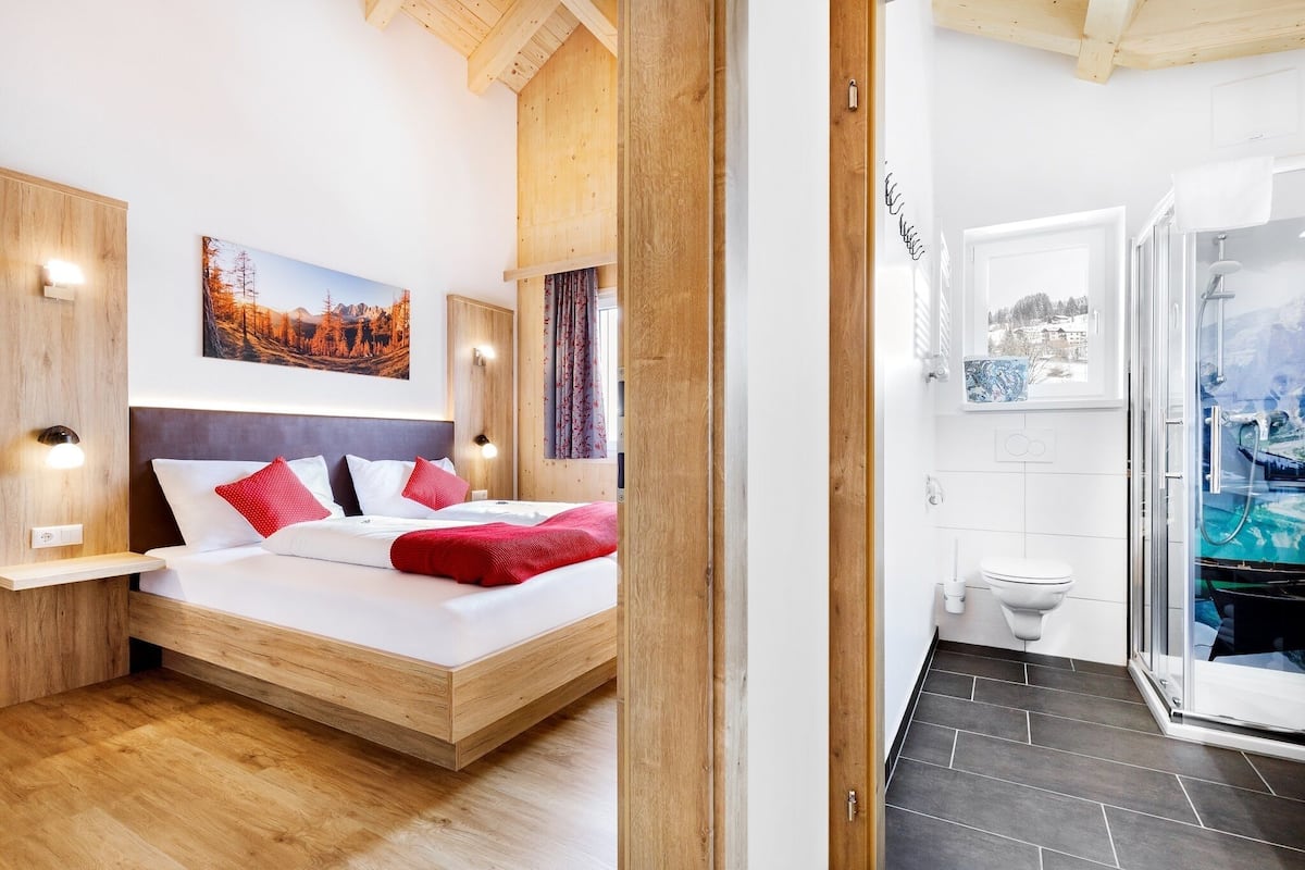 Um quarto moderno com uma cama de madeira, uma mesa de cabeceira e uma luminária na parede.