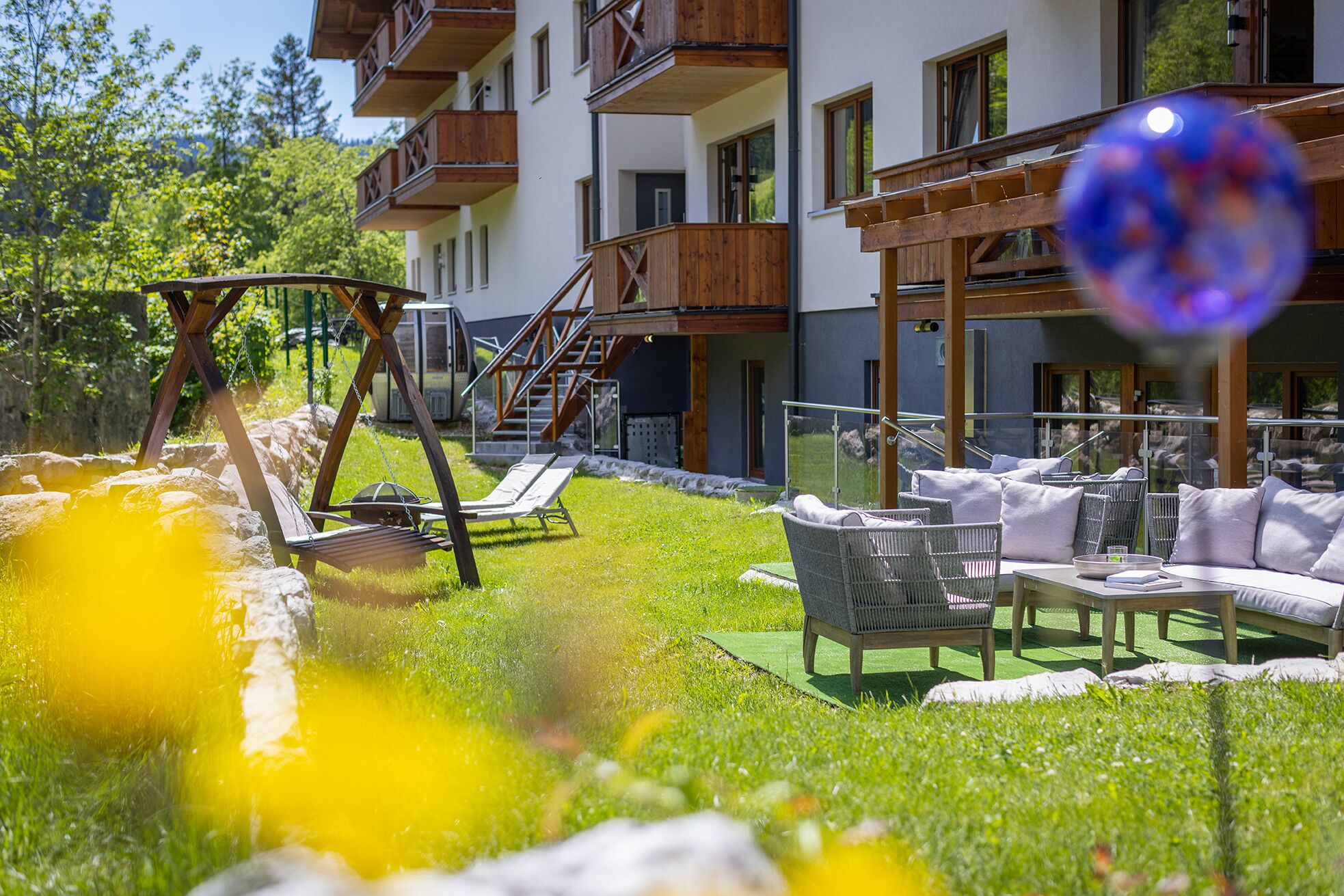 A hotel with outdoor seating, a swing set, and a pool area.