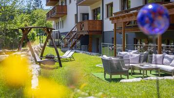 A hotel with outdoor seating, a swing set, and a pool area.