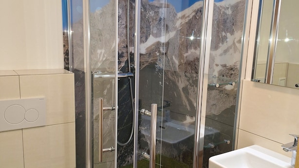 A modern bathroom with a glass-enclosed shower, a white toilet, and a wooden vanity with a sink.