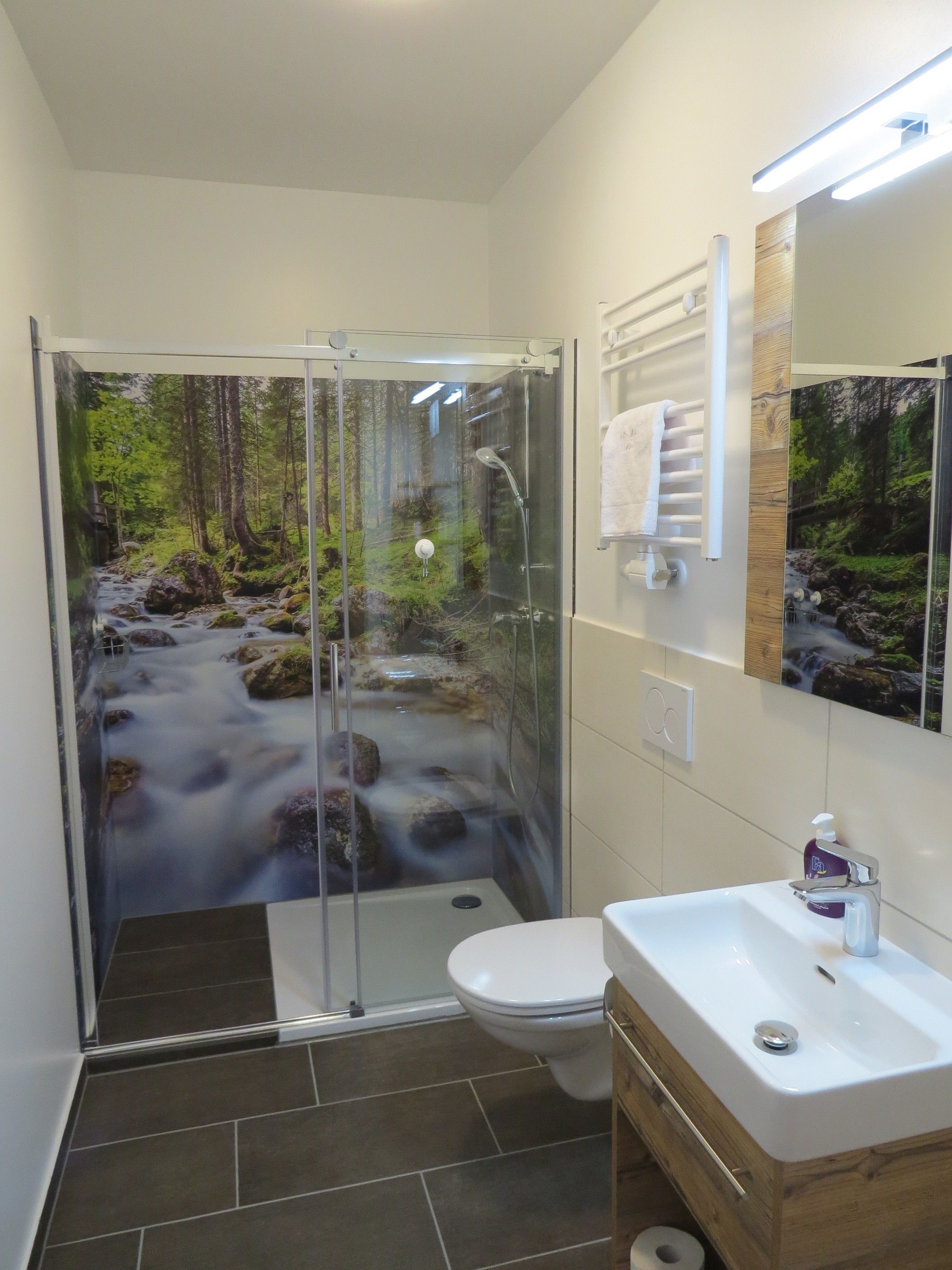 Un baño moderno con ducha acristalada, un lavabo blanco y un espejo.