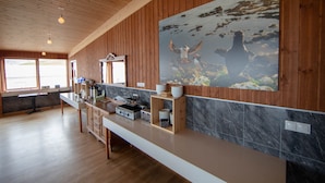 A modern kitchen with wooden paneling, a marble backsplash, and a large wildlife painting. - Hotel Breidavik (Vesturbyggð)