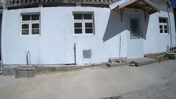 A white building with a balcony, a door with a metal gate, and a small window.