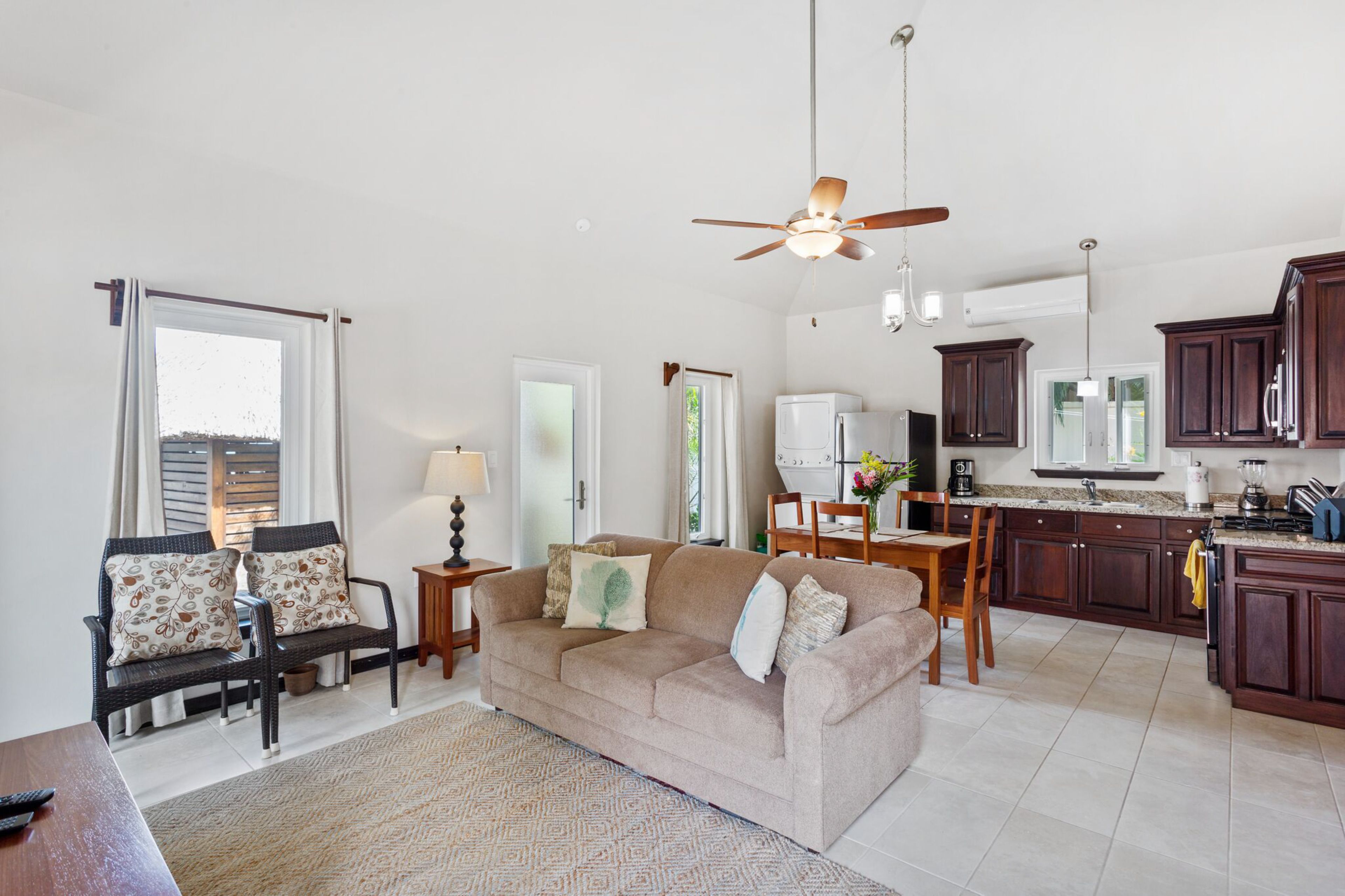 A living room with a sofa, a dining table, and a kitchen area with cabinets and appliances.