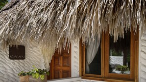A thatched-roof building with a wooden door and window, a sign reading "KA'AN", and a small planter with plants. - El Corazón Boutique Hotel - Adults Only with Pool & Beach Club Access (Isla Holbox)