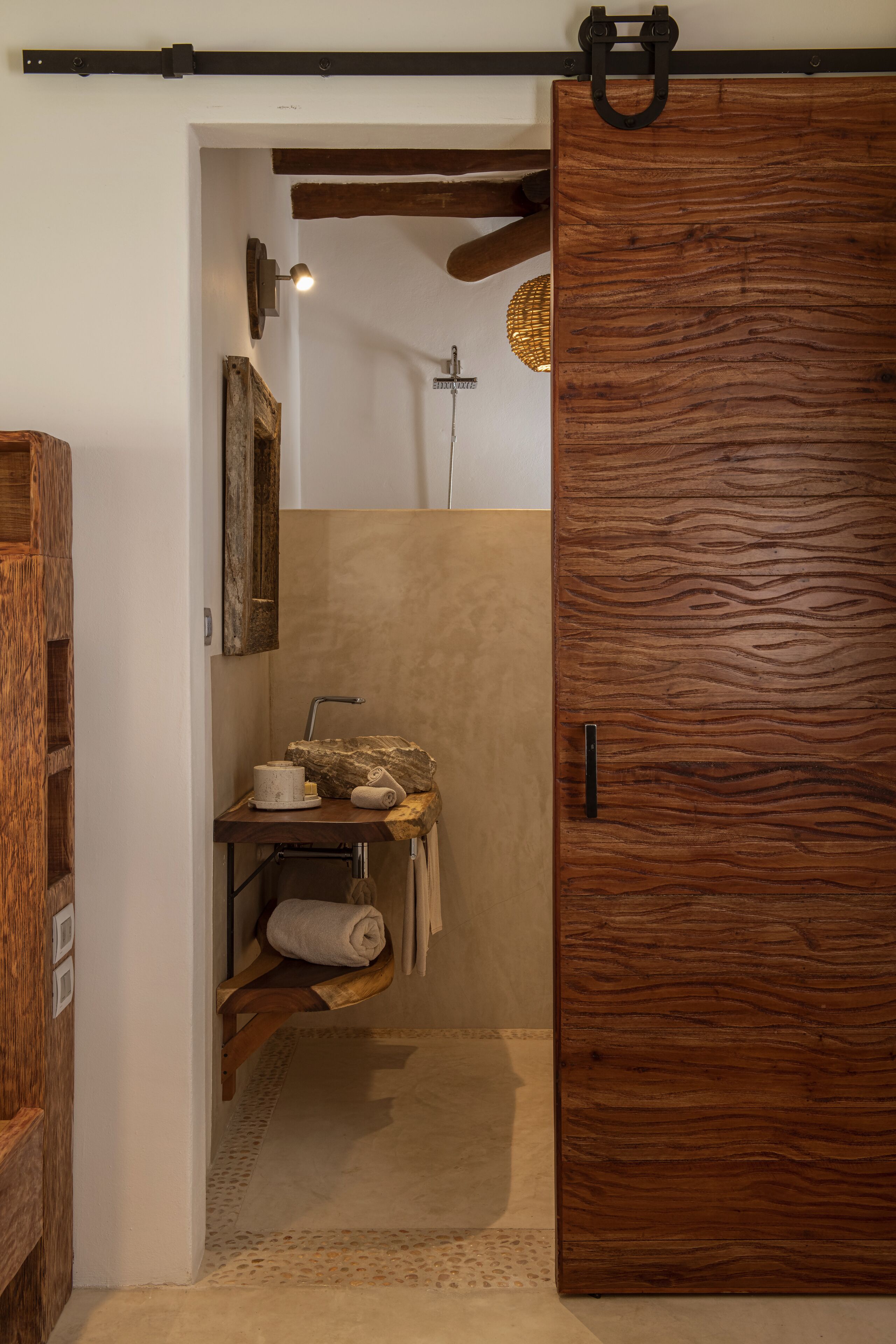 Un baño con puerta de madera, un perchero y un estante con artículos de aseo.
