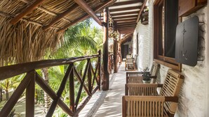 A covered outdoor area with wooden benches and a thatched roof, surrounded by lush greenery. - El Corazón Boutique Hotel - Adults Only with Pool & Beach Club Access (Isla Holbox)