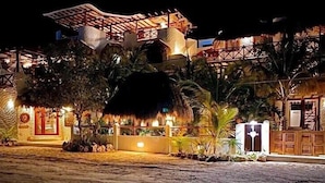A beachfront property with a thatched-roof structure, a wooden fence, and tropical vegetation. - El Corazón Boutique Hotel - Adults Only with Pool & Beach Club Access (Isla Holbox)