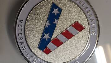 A circular emblem with a textured silver background, featuring a blue and red striped design with stars, and text reading "GOOGLE CELEBRATES VETERAN-LED BUSINESSES".