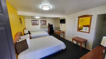 A hotel room with two beds, a desk, a chair, a TV, and a mirror.