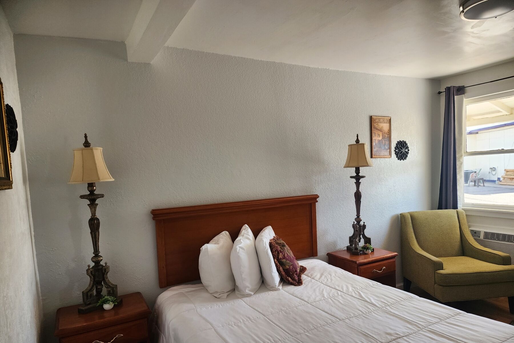 Ett hotellrum med en säng, två sängbord, en stol och ett fönster med utsikt.