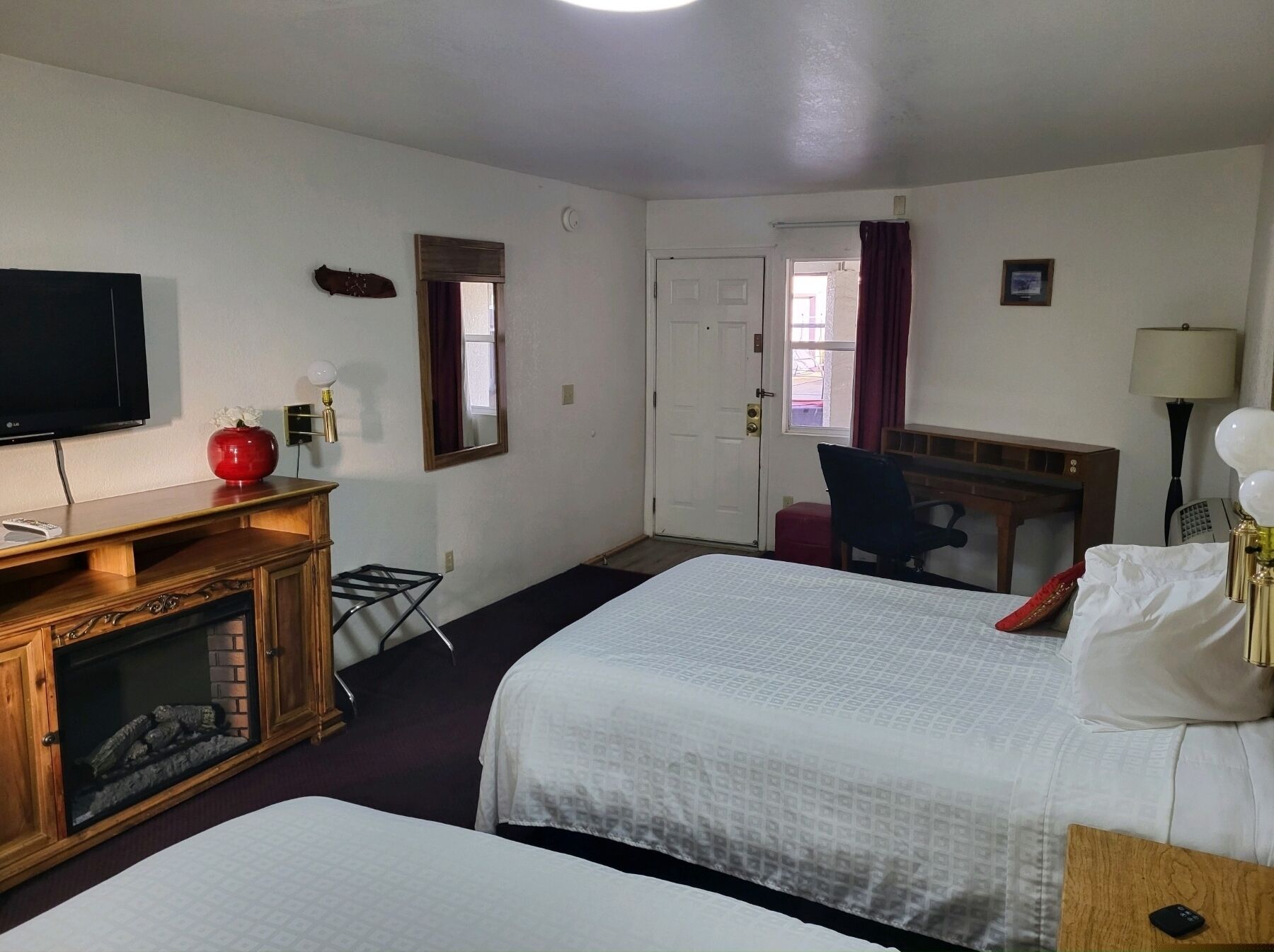A hotel room with two beds, a TV, a desk, and a chair.