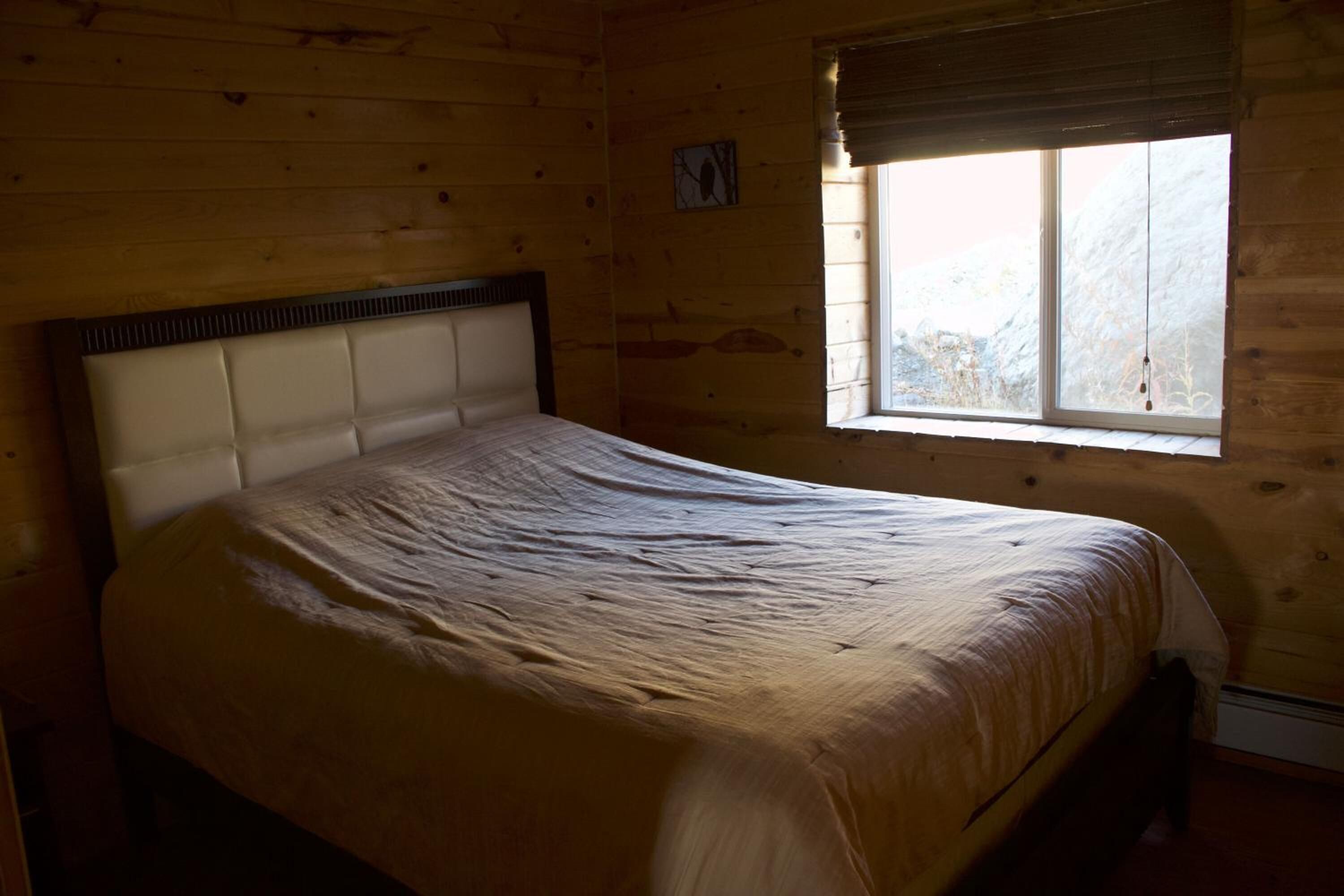 A bed in a wooden room with a window.