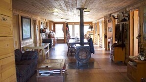 A log cabin interior with a long dining table, a sofa, and a coffee station. - Alpine Creek Lodge (Cantwell)
