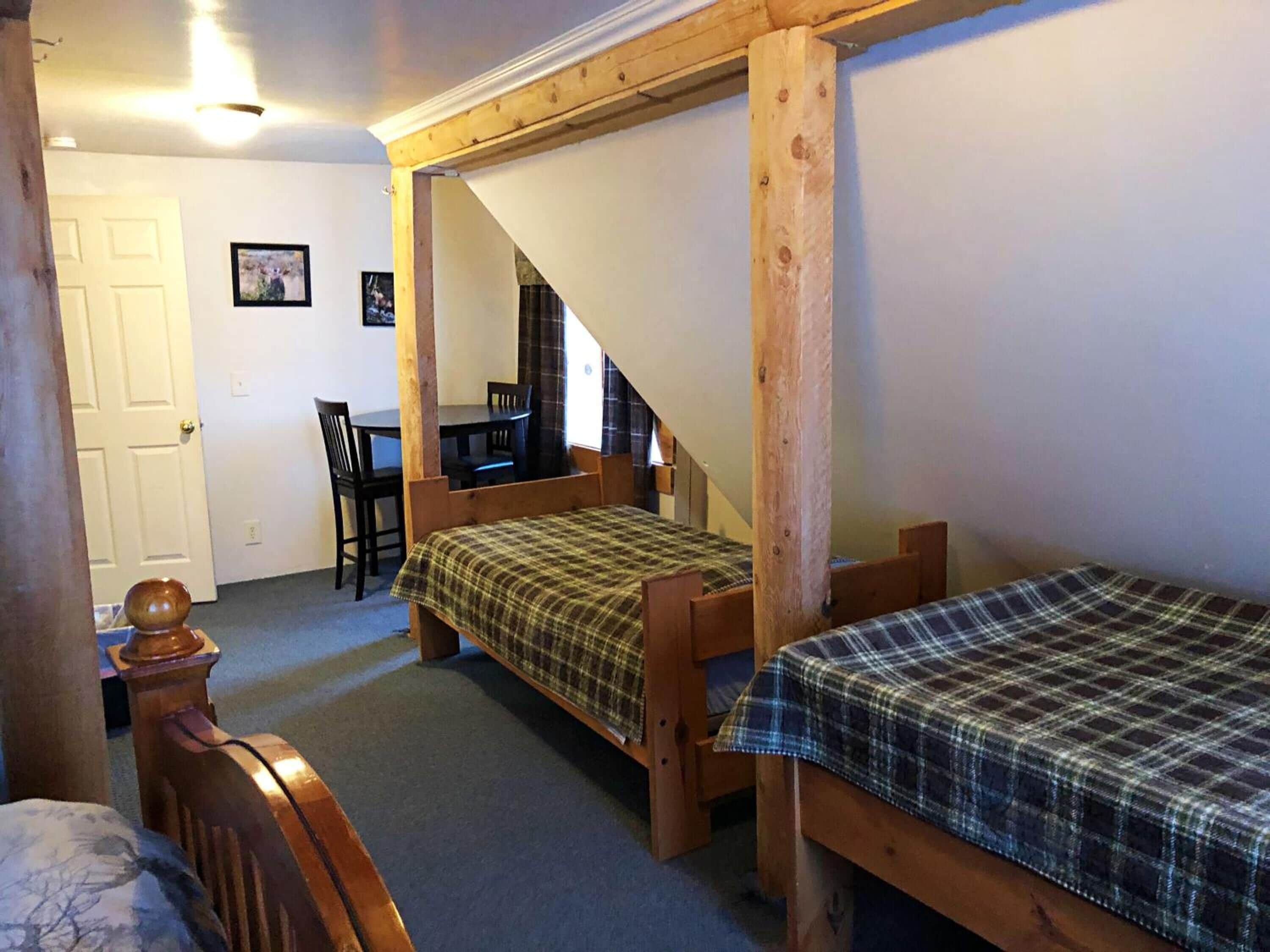 A room with two wooden beds, a desk, and a chair.