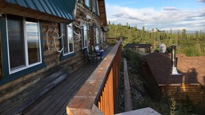 A log cabin with a deck, large windows, and antlers displayed outside. - Alpine Creek Lodge (Cantwell)