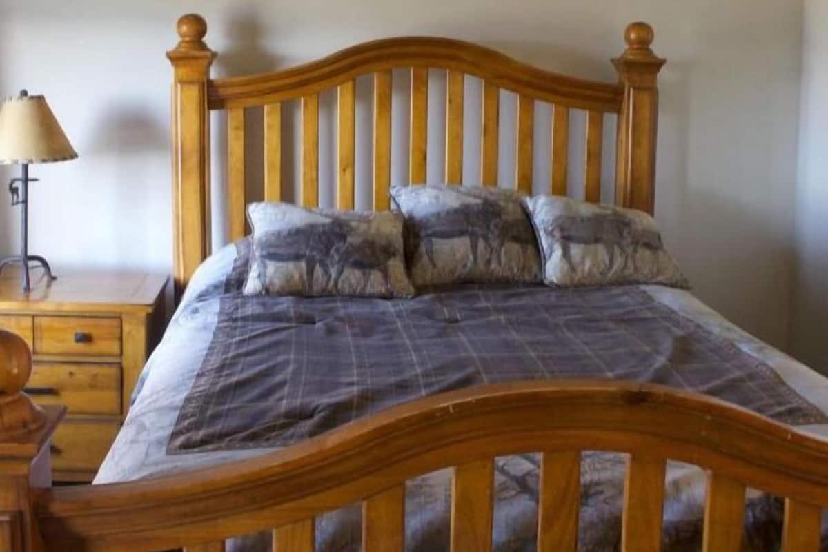Un lit en bois avec une tête de lit, une table de chevet et une lampe.