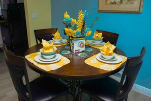 A dining table set with plates, bowls, and napkins, surrounded by chairs. - Jubilee Gardens Freeport (Freeport)