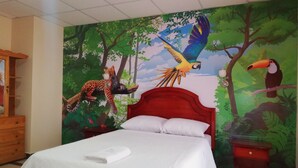 A bed with a white bedspread and pillows, a red headboard, and a mural of jungle animals on the wall behind. - Hotel Unicornio (Coca)