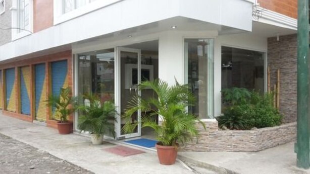 A hotel entrance with a covered porch, glass doors, and potted plants. - Hotel Unicornio (Coca)