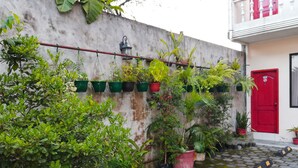 A courtyard with potted plants, a red door, and a cobblestone path. - Hotel Unicornio (Coca)
