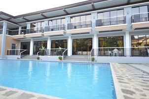 Un bâtiment moderne doté d’une piscine, de balcons et de grandes fenêtres.