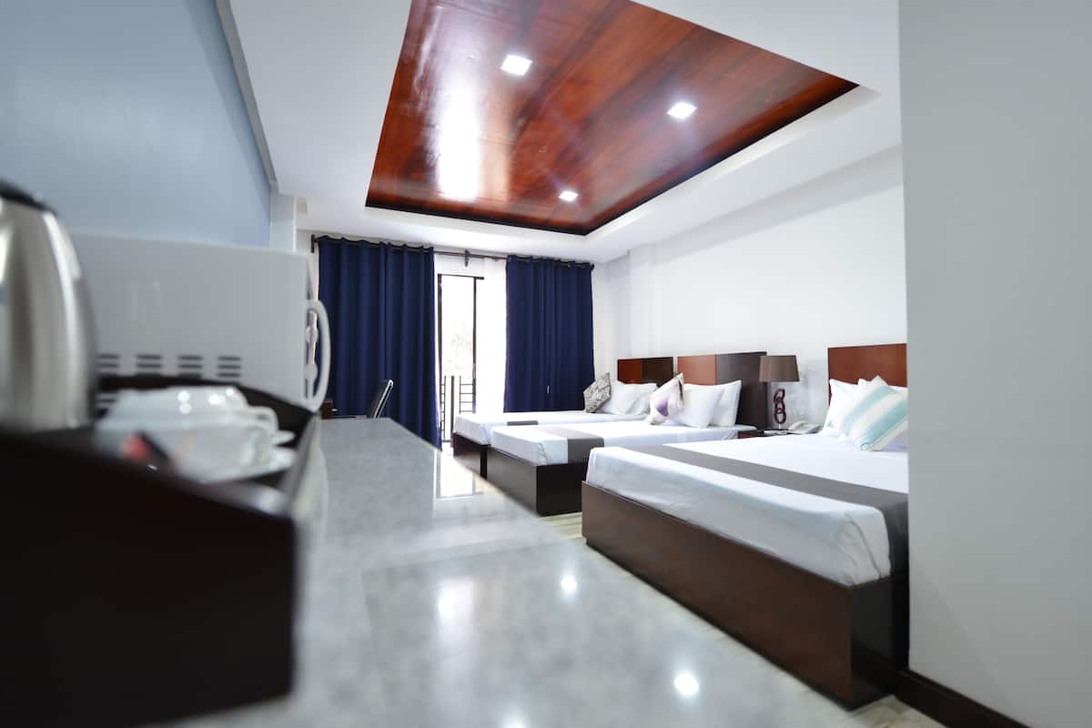 Quarto de hotel com teto de madeira, duas camas, uma mesa com telefone e janela com cortinas.
