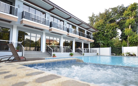 A modern hotel with a pool area, multiple balconies, and a spa.