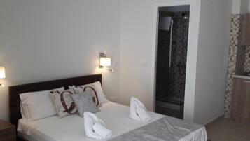 Una cama bien hecha con ropa blanca y toallas, un cabecero de madera y un aire acondicionado instalado en la pared.