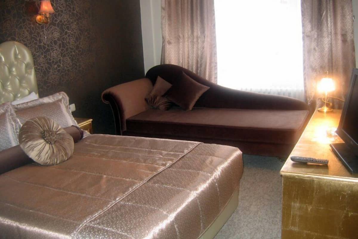 A hotel room with a bed, a sofa, a TV, and a lamp.